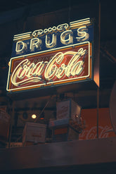 Yuqi Chen - An illuminated vintage Coca-Cola neon sign against a dark background, showcasing retro branding.
